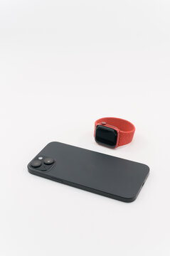 immagine editoriale illustrativa primo piano di Apple iphone 15 plus con Apple Watch Product Red su superficie bianca