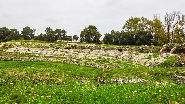 Static wide shot of ancient temple ruins the Teatro Greco a greek theatre in Sicily, italy with ancient elements from the third century and view of the green landscape 