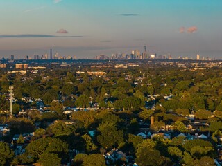 Aerial view of the New York City skyline, as viewed from Long Island with green trees.