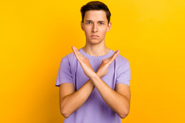 Portrait of determined man in t-shirt showing x sign with crossed hands meaning stop isolated...