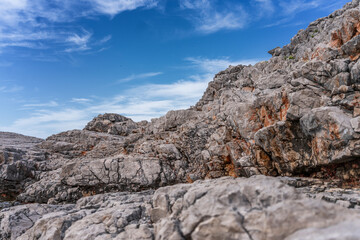 Gray stone rocks against a blue sky with clouds, nature background