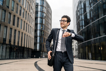 The manager is in a hurry, looking at the clock, happy going to work in a new office every day routine. A young confident lawyer agent in real estate glasses in business clothes.