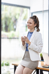 Fototapeta premium Portrait of business canada woman in casual wear holdng clipboard, smiling and looking at camera while standing in modern office room.