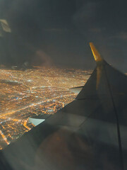vertical photo view from the airplane window to the wing and the city at night. soft focus.