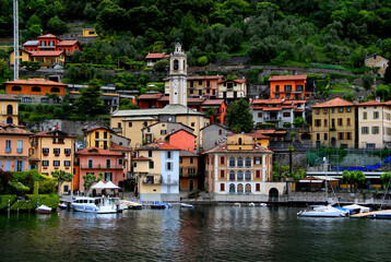Landscape view of one of the many small towns on Lake Como with a church and numerous boats in the...