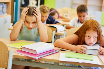 Worried female friends sitting on bench in class