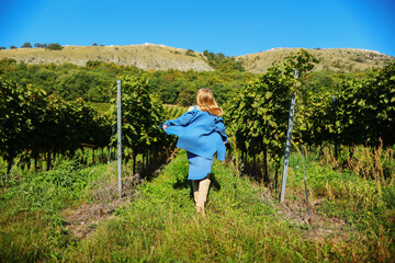 A long-haired girl running through a vineyard on a sunny summer day