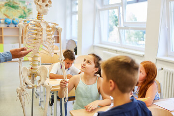 Female student touching human skeleton in class