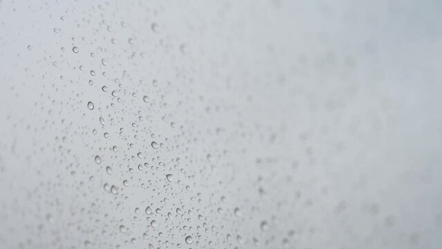 Rainy glass as rain drops hits a window during a gloomy and overcast weather.