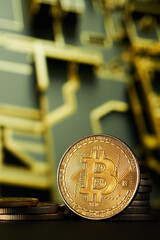 Closeup of Golden Bitcoin cryptocurrency vertically with blurred computer printed circuit background