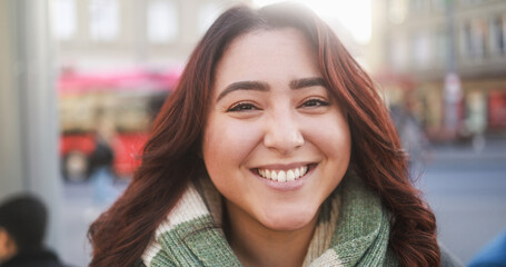 Young multiracial woman smiling in front of camera at bus station during winter time - Urban...