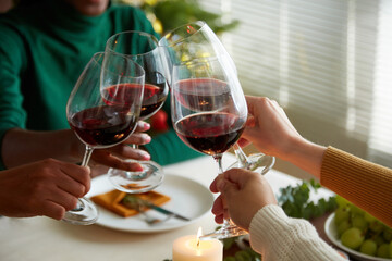 Group of friends toasting with glasses of red winter, celebrating Christmas at home
