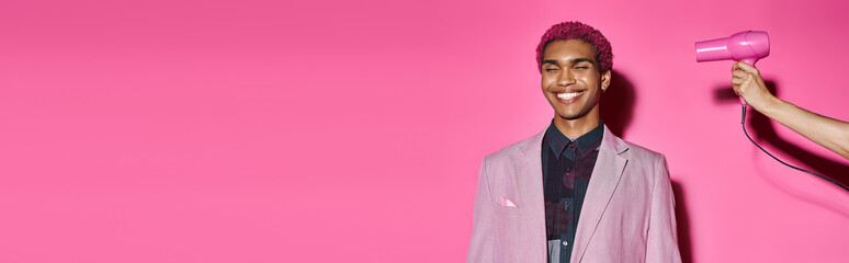 smiley man posing unnaturally on pink backdrop with closed eyes, hand with hairdryer, banner