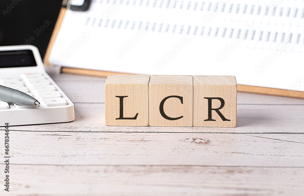 Poster lcr- liquidity coverage ratio word on a wooden block with clipboard and calcuator