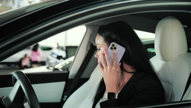 Angry young lady sitting in the car while having unpleasant conversation on the mobile phone. Transport, technology, trip, business concept. Slow motion