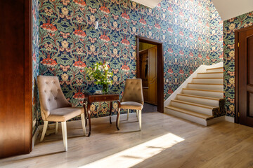 A coffee table with a bouquet and a cup, standing near the stairs to the second floor