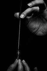 female hand elegantly holding an ink pen with a metal tip close-up on a black background. classic...