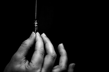 female hand elegantly holding an ink pen with a metal tip close-up on a black background. classic fountain pen isolated macro black and white. copy space - obrazy, fototapety, plakaty