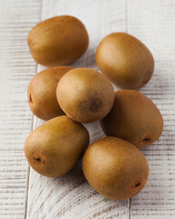 Ripe juicy green kiwis on a white wooden background. Fruit harvesting.