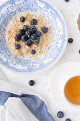 Oatmeal with blueberries for breakfast. Beautiful breakfast setting on a white background. Healthy food with berries.