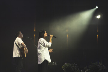 A duet of singers is performing a song on stage. Worship band sings and worships God in the church. Church service. - obrazy, fototapety, plakaty