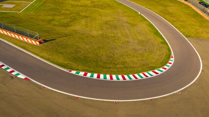 Aerial view of a curve of a racing circuit. The track is empty and there are no cars racing. - obrazy, fototapety, plakaty