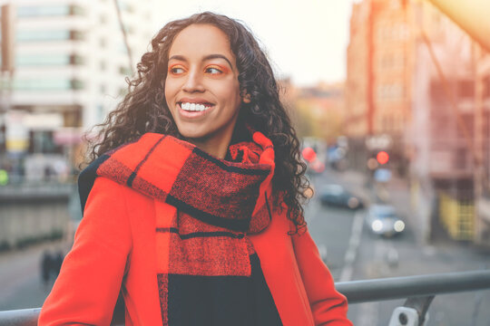 Facial close-up portrait of young attractive smiling female walking down streets of the city and enjoying sunny day toned image