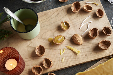 Handmade fabrication of Christmas candles from melted bees wax and nut shells