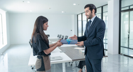 Office meeting room, after accomplishing their business targets, male executive rewards female team...