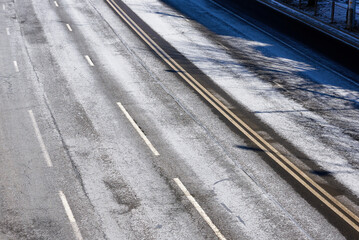 Asphalt road covered with salt stains. Road anti-icing, pre-treatment and de-icing highway in the city in winter season. Salting roads view from above