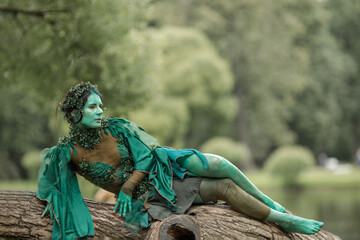 A mystical green dryad in the forest in the background. A fabulous mythical creature.