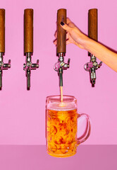 Female hand pouring light beer from tap into chilled glass. Beer forms thick, foaming as it cascades into mug.