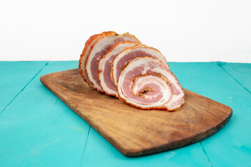 Pork meat roulade sliced on a wood chopping board, side view