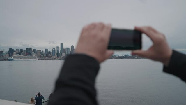 Man Taking Photo of Seattle Skyline from His Phone on Ferry to Bainbridge Island and Enjoying The Skyline View from The Sea