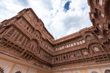 Obraz premium Look up at the red and yellow castle standing majestically on the hill. Mehrangarh Fort is in Jodhpur, Rajasthan, India. UNESCO World Heritage Site.