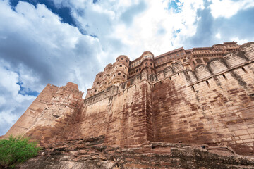 Look up at the red and yellow castle standing majestically on the hill. Mehrangarh Fort is in Jodhpur, Rajasthan, India. UNESCO World Heritage Site.