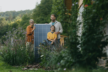 Father mother and daughter standing in garden with solar panel. Solar energy and sustainable...