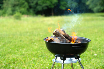 Burning fire flame in round grill bbq. Cooking outdoors in a meadow.