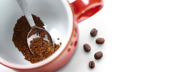 Looking down onto a red coffee mug with instant coffee granules inside it along with a silver spoon and coffee beans ready to make a fresh cup of hot coffee isolated against a transparent background.