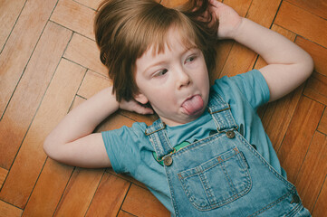 Indoor candid portrait of a caucasian blond child lying on the floor