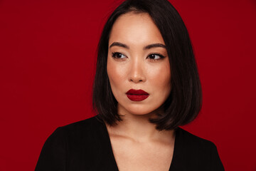 Portrait of beautiful woman looking away while standing isolated over red wall