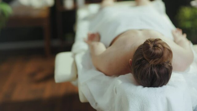 Healthcare time. relaxed modern middle aged woman in spa salon laying on massage table.