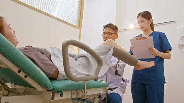 Asian doctor conducting a pelvic exam on a patient at hospital or in premium clinic. gynecological examination. Well-being of women concept