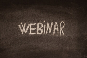 English word webinar written in chalk on a black board. Self-learning, communication.
