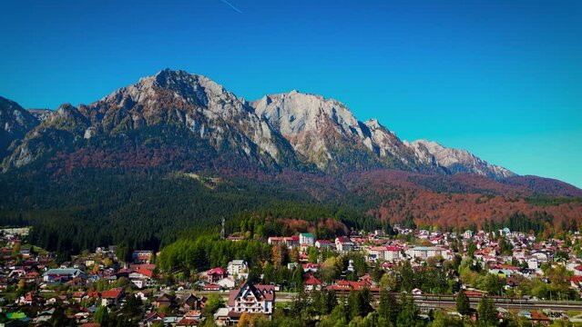 Drone footage of the cityscape of Busteni and Bucegi Mountains in a beautiful sunny day, Romania