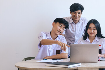 Group of Asian teenage students wearing school uniform studying together in classroom 