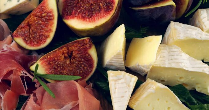 Figs, jamon, spinach leaves and blue cheeses on a wooden board. Snacks set.