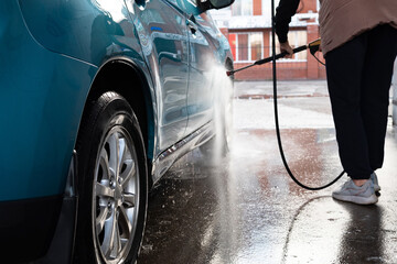 Woman washing her car in a self-service car wash station.Car wash self-service. - obrazy, fototapety, plakaty