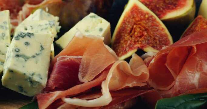 Figs, jamon, spinach leaves and blue cheeses on a wooden board. Snacks set.