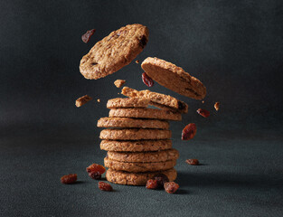 Oatmeal cookies with raisin falling into a stack close up on a gray background